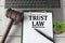 TRUST LAW - words on a white sheet on the background of a laptop, a court hammer and a pen