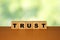 Trust message word on a wooden desk on cube blocks with a green nature