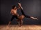 Trust and strength. Two male contemporary dancers performing a dramatic pose in front of a dark background.