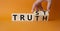 Trust and Truth symbol. Businessman Hand turns a cube and changes the word Truth to Trust. Beautiful orange background. Business