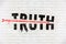 Truth destroyed with an arrow of conspiracy, fake news, disinformation, propaganda, alternative facts, painted on old white wall