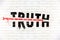 Truth destroyed with an arrow of fake news painted on old white wall