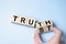 Truth instead of trust. Hand turns dice and changes the word Trust to Truth