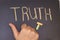 TRUTH written in chalk on blackboard and hand showing thump up