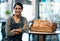 Try it, I know youll like it. a young woman serving a selection of freshly baked breads in her bakery.