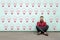 Try to find idea or problem solving. Young thoughtful bearded business man in red shirt sitting on floor and thinking what to do