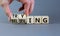 Trying and believing symbol. Businessman turns wooden cubes and changes the word Believing to Trying. Beautiful grey table grey