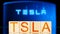 tsla. wooden blocks with tsla lettering on blue background with electric charger.