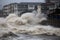 tsunami waves crash over seawalls, flooding coastal cities and towns