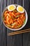 Tteokbokki is one of the most popular Korean street foods in Korea close-up in a bowl. Vertical top view