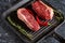 Ttwo fresh, juicy organic ripened ribeye steaks in a grill pan with a pod of red chili peppers and sprigs of rosemary