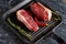 Ttwo fresh, juicy organic ripened ribeye steaks in a grill pan with a pod of red chili peppers and sprigs of rosemary