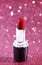 Tube of Classic Bright Red Lipstick on a Pink Glittery Background