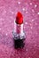 Tube of Classic Bright Red Lipstick on a Pink Glittery Background