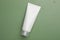 Tube of face cleansing product on green background, top view