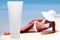 Tube of sun lotion with slim tanned woman on a beach behind.