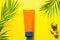 Tube of sunscreen on a yellow summer background with palm leaves and the sun. Tanning agent, skin protection, a trip to the sea,
