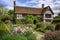 tudor house, surrounded by picturesque garden, with blooming flowers and shrubbery