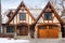 Tudor style family house exterior with gable roof and timber framing. Wooden garage doors in home cottage. Created with generative