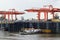 Tug alongside pier on River Thames UK with Two Gantry Cranes in Background