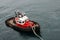 A tug boat drags the boat dock lines from a cruise ship to the dock to be tied up