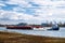 A tug boat navigates down river hauling a barge with gravel