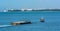 A tug boat pulls a load of sand bound for land reclamation in coastal waterway