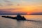 A tug on the river pushes a barge with sand or gravel. Sunset on the Volga river in Russia in July. Orange sun in the sky