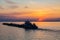 A tug on the river pushes a barge with sand or gravel. Sunset on the Volga river in Russia in July. Orange sun in the sky