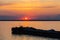 A tug on the river pushes a barge with sand or gravel. Sunset on the Volga river in Russia in July. Orange sun in the sky
