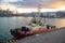 A tug of a ship stands moored at the pier on a summer evening during sunset. Sea harbor. Port cranes unload cargo