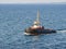 A tugboat navigates on the sea, in the background the coast can be seen