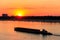 Tugboat pushing heavy long barge on the river Dnieper at sunset