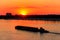 Tugboat pushing heavy long barge on the river Dnieper at sunset