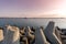 Tugboat sailing in sea to tow ship to port. Tetrapod breakwaters in harbor. Beautiful sunset over the pier