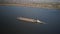 A tugboat ship pushes a barge upstream of the river to transport bulk materials. Aerial photography with a quadcopter or