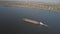 A tugboat ship pushes a barge upstream of the river to transport bulk materials. Aerial photography with a quadcopter or a drone.