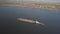 A tugboat ship pushes a barge upstream of the river to transport bulk materials. Aerial photography with a quadcopter or a drone.