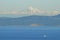 A tugboat traverses and ocean pathway with the San Juan Islands and the beautiful Mount Baker in behind