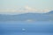 A tugboat traverses and ocean pathway with the San Juan Islands and the beautiful Mount Baker in behind