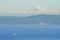 A tugboat traverses and ocean pathway with the San Juan Islands and the beautiful Mount Baker in behind