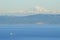 A tugboat traverses and ocean pathway with the San Juan Islands and the beautiful Mount Baker in behind