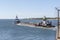 Tugs pushing and pulling barge through hurricane barrier