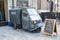 Tuktuk parked with blackboard advertisement signs outside a boutique.  Blackboard advertising food and drinks