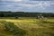 TULA, RUSSIA - JULY 30, 2019: green haymaking tractor on summer field before storm - telephoto shot with selective focus