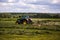 TULA, RUSSIA - JULY 30, 2019: green haymaking tractor on summer field before storm - telephoto shot with selective focus