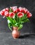 Tulips in clay pitcher on black background. Pink tulips. Flowers in vase