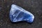 tumbled Dumortierite gemstone on dark g background