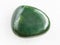 tumbled green nephrite gemstone on white marble