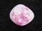 tumbled pink Sodalite gemstone on dark